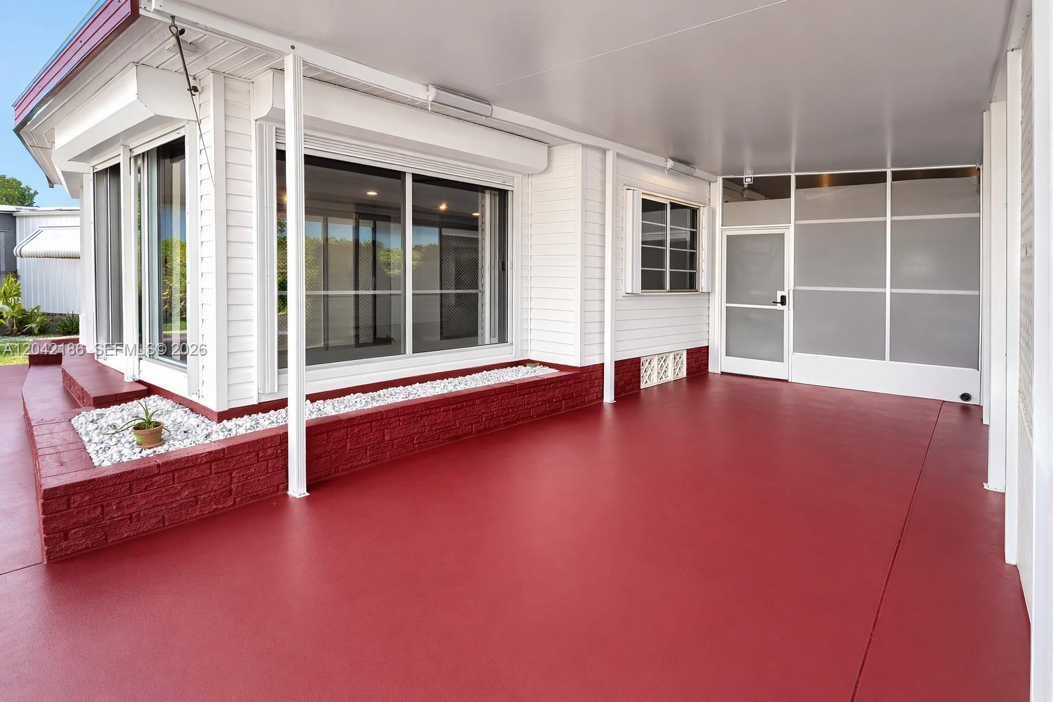 A covered patio features a red painted floor, a brick planter, and white siding — 2260 SW 85th Way, Davie FL 33324, DAVIE, FL