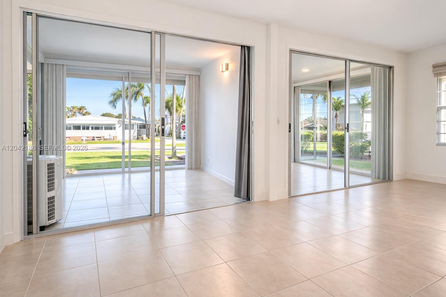 A bright room features large sliding glass doors, light tile flooring, and white walls — 2260 SW 85th Way, Davie FL 33324, DAVIE, FL