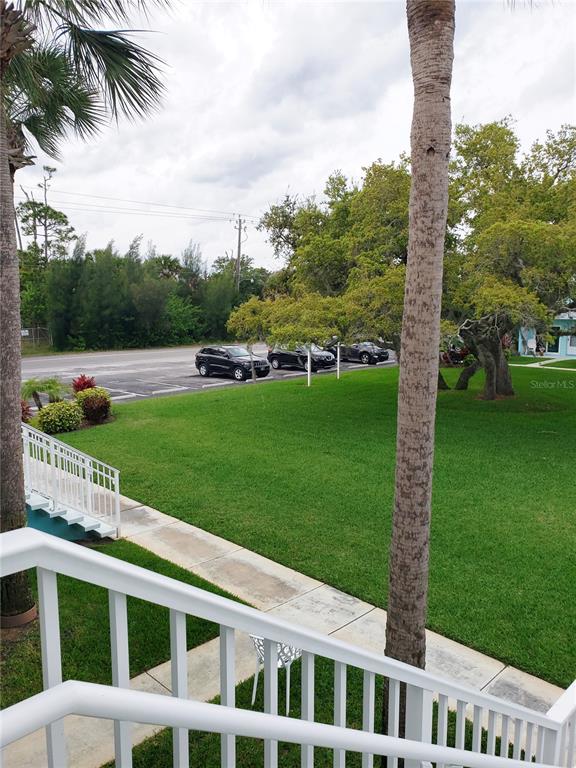 A view from an elevated balcony overlooking a grassy lawn, a parking lot, and trees — 541 S PENINSULA AVENUE UNIT A21, NEW SMYRNA BEACH, FL