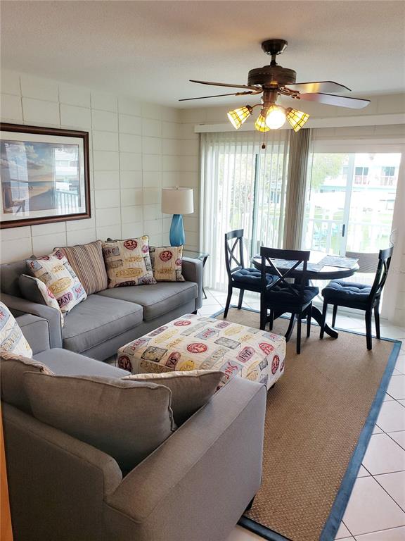 A living room features a gray sofa, a patterned ottoman, and a dining area nearby — 541 S PENINSULA AVENUE UNIT A21, NEW SMYRNA BEACH, FL