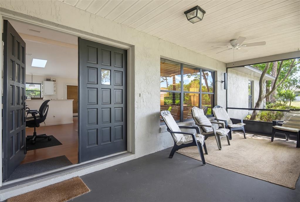 A screened-in patio with dark chairs and a rug overlooks a yard through large windows — 3048 WILLOW OAK DRIVE, EDGEWATER, FL