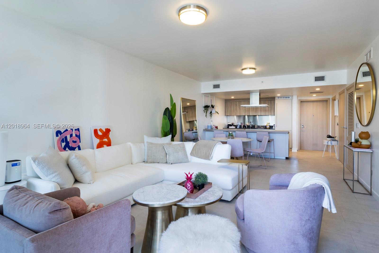 A living room with a white sectional sofa, two purple armchairs, and an open kitchen — 1000 Brickell Plz # 2411, Miami FL 33131, MIAMI, FL