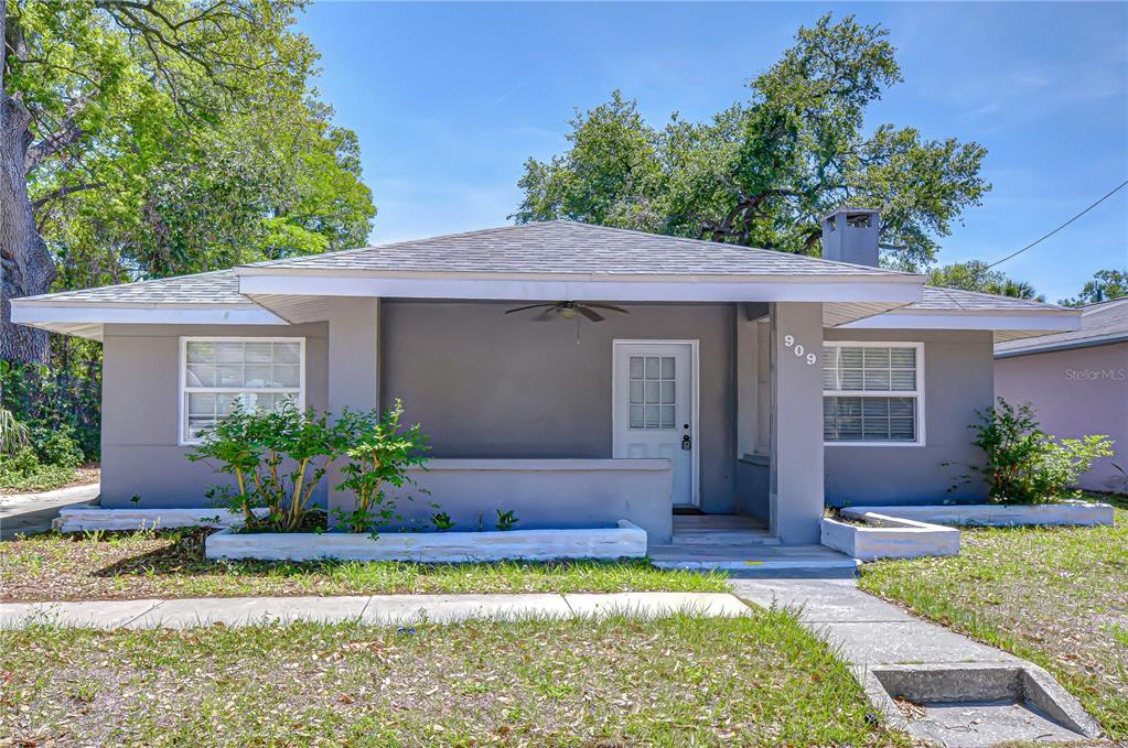 A single-story gray house features a front porch, a chimney, and a small garden bed — 909 HART STREET, CLEARWATER, FL