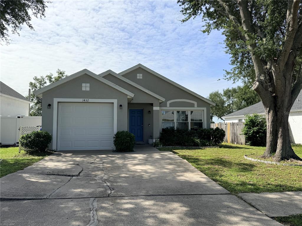 A single-story house with a gray exterior, a white garage door, and a blue front door — 1432 DEW BLOOM ROAD, VALRICO, FL