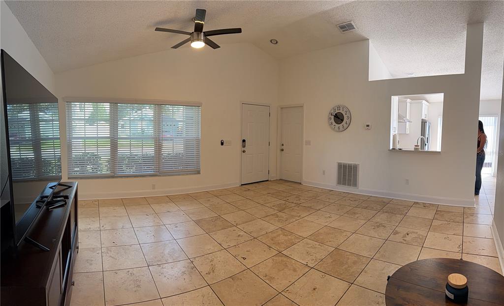 A living room with vaulted ceilings, tile flooring, a ceiling fan, and a wall clock — 1432 DEW BLOOM ROAD, VALRICO, FL
