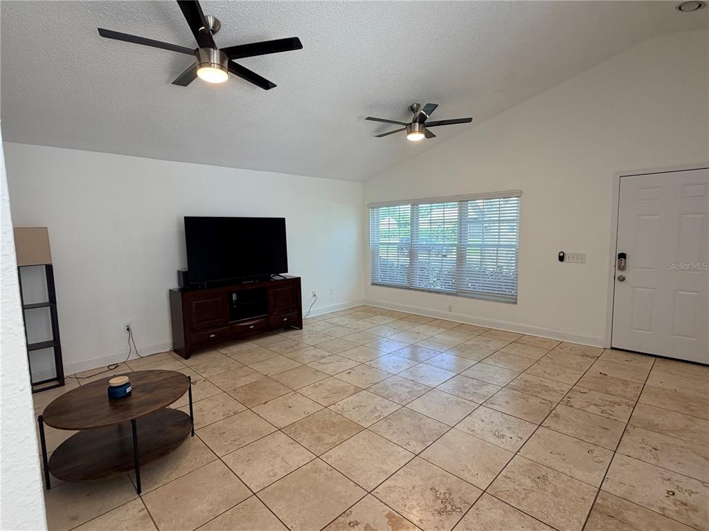A living room features tile flooring, two ceiling fans, a television console, and a window — 1432 DEW BLOOM ROAD, VALRICO, FL