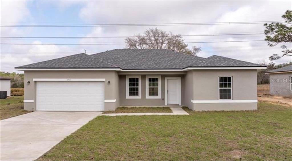 A single-story house with a gray stucco exterior, a two-car garage, and a shingled roof — 9809 N SWANEE TERRACE, DUNNELLON, FL
