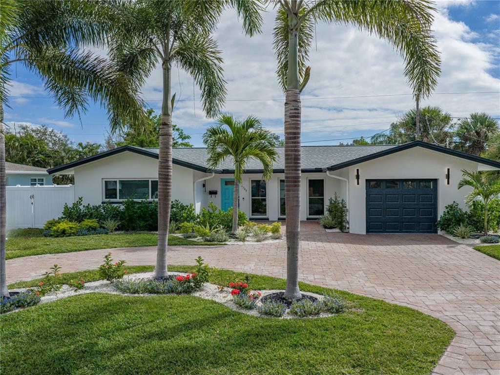 A single-story house with a white exterior, dark garage door, and a paved circular driveway — 6709 CARDINAL DRIVE S, ST PETERSBURG, FL