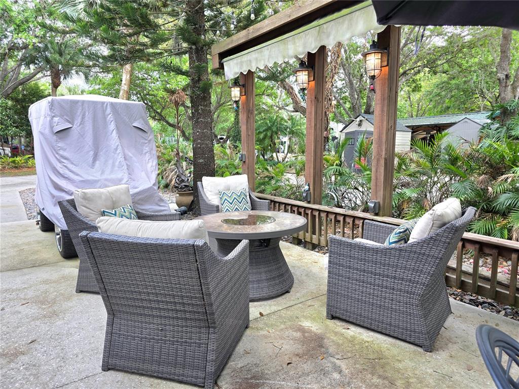 A patio features four wicker chairs surrounding a round fire pit table under a pergola — 159 HORSESHOE BEND, LAKE WALES, FL