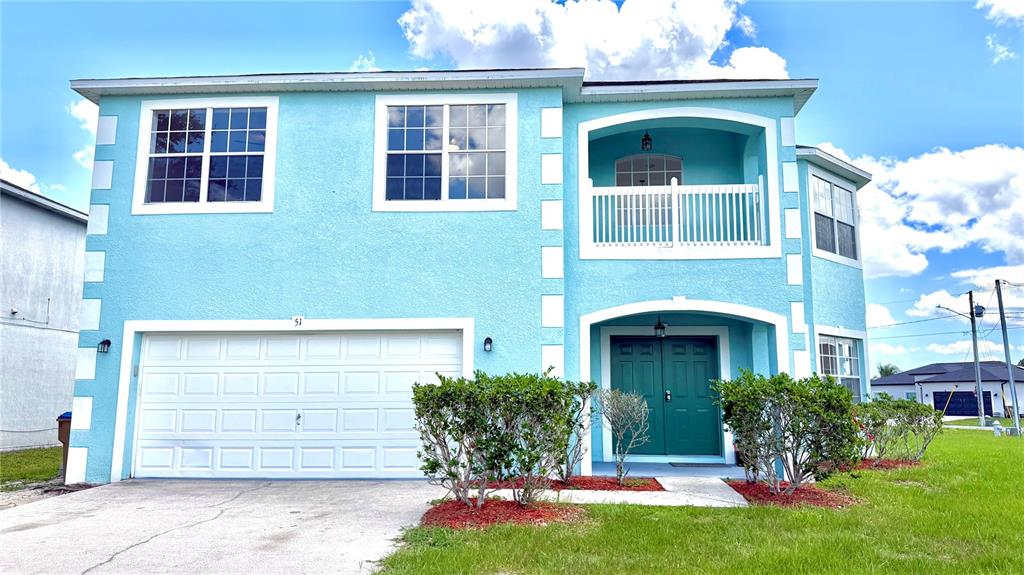 A two-story light blue house with a white garage door and a green front door — 51 ANDORA COURT, KISSIMMEE, FL
