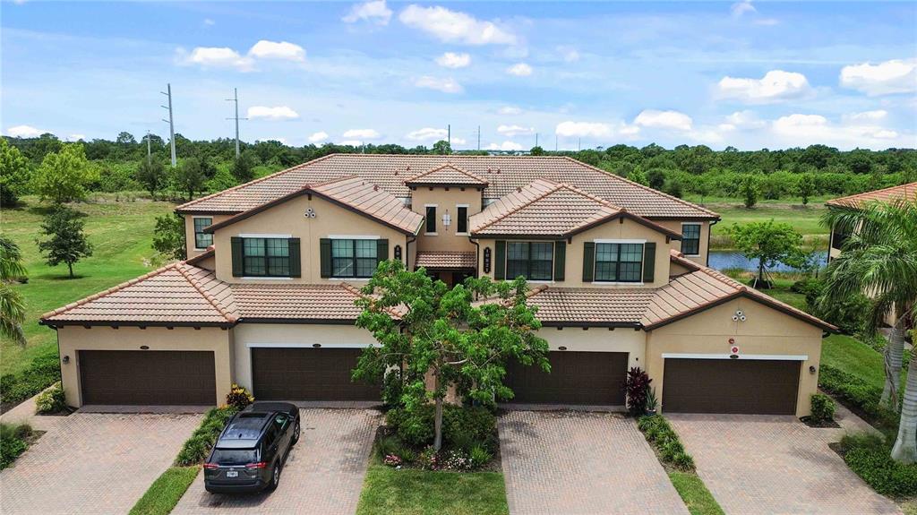 An aerial view of a two-story residential building with four garage doors and tile roofs — 10821 TARFLOWER DRIVE UNIT 202, VENICE, FL