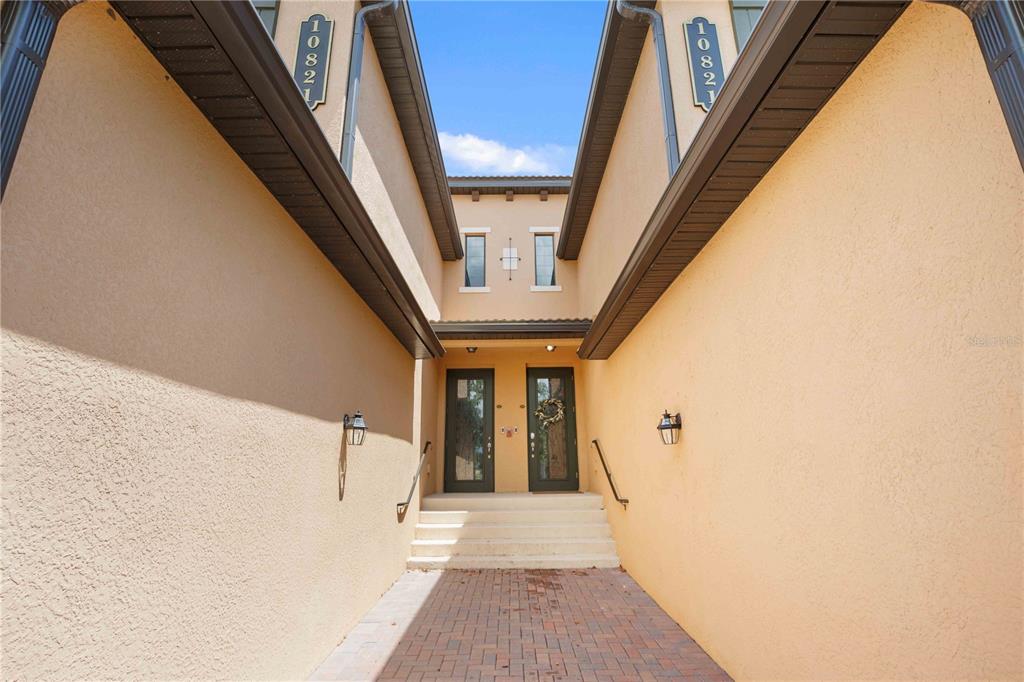 The exterior view shows a paved walkway leading to two front doors with stairs — 10821 TARFLOWER DRIVE UNIT 202, VENICE, FL