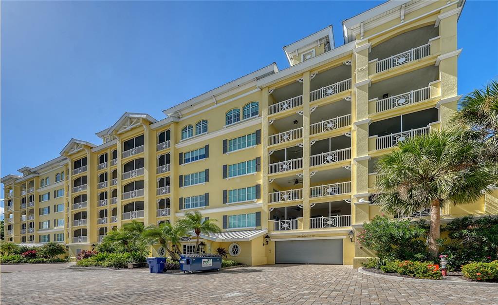 A multi-story yellow apartment building with screened balconies and a ground-level parking garage — 1308 OLD STICKNEY POINT ROAD UNIT W32, SARASOTA, FL