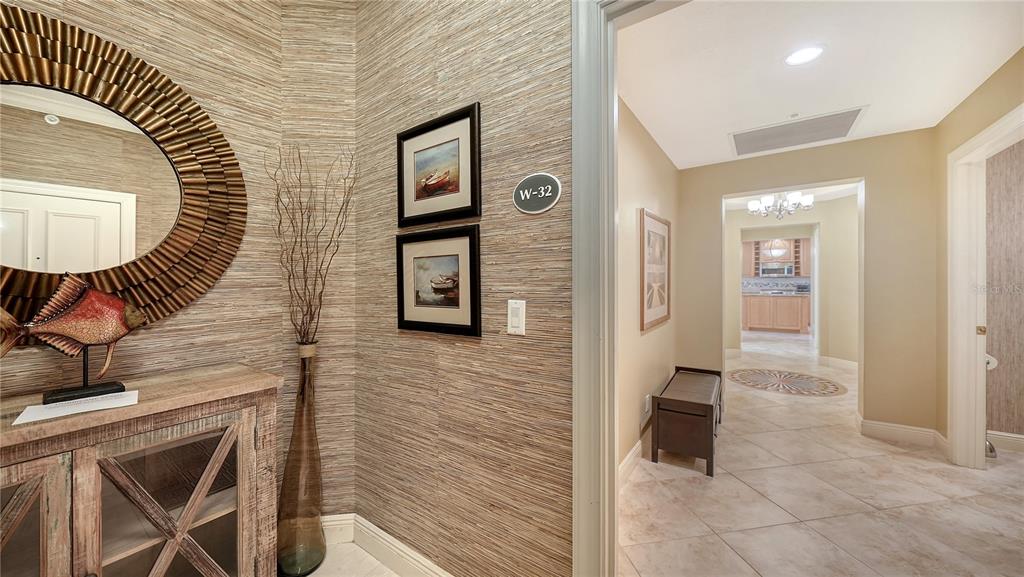 A foyer with textured wallpaper, a round mirror, and a doorway leading to a hallway — 1308 OLD STICKNEY POINT ROAD UNIT W32, SARASOTA, FL