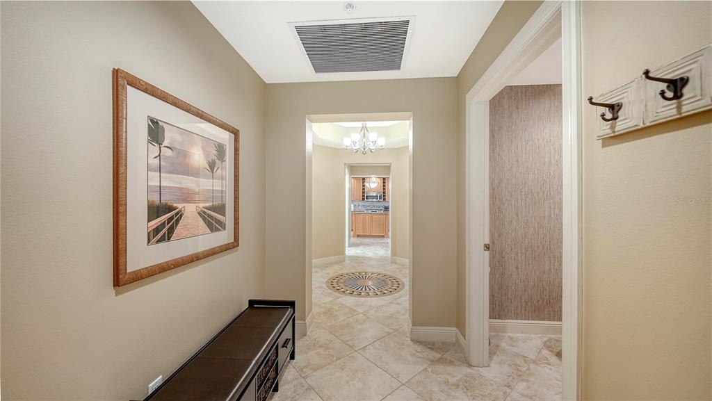 A tiled hallway features a bench, framed artwork, and a view into a kitchen — 1308 OLD STICKNEY POINT ROAD UNIT W32, SARASOTA, FL
