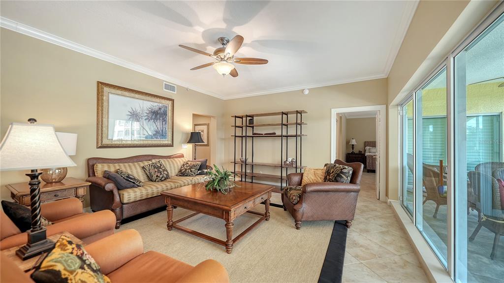 A living room features a sofa, armchairs, a coffee table, and a large shelving unit — 1308 OLD STICKNEY POINT ROAD UNIT W32, SARASOTA, FL