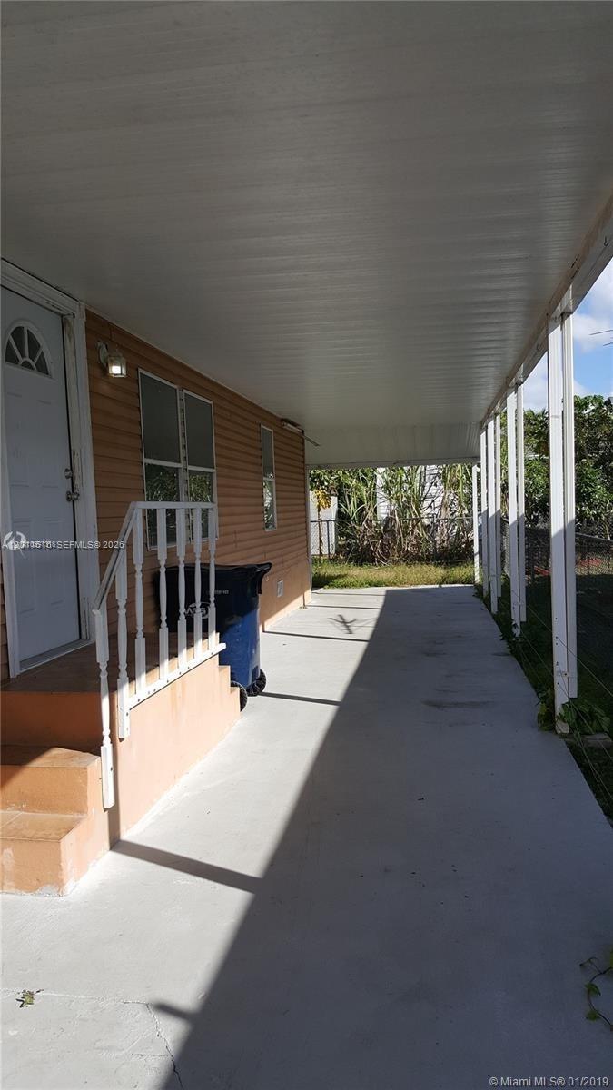 A covered concrete patio runs alongside the exterior wall of a house with light-colored siding — 19800 SW 180th Ave # 32, Miami FL 33187, MIAMI, FL