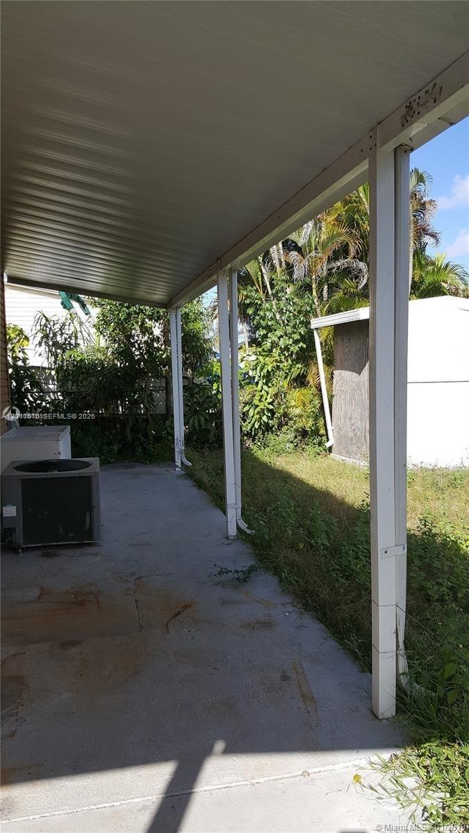 A covered concrete patio area features white support posts and an outdoor air conditioning unit — 19800 SW 180th Ave # 32, Miami FL 33187, MIAMI, FL