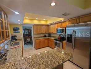 A kitchen features wood cabinets, granite countertops, stainless steel appliances, and a recessed ceiling — 5409 PALM AIRE DRIVE, SARASOTA, FL