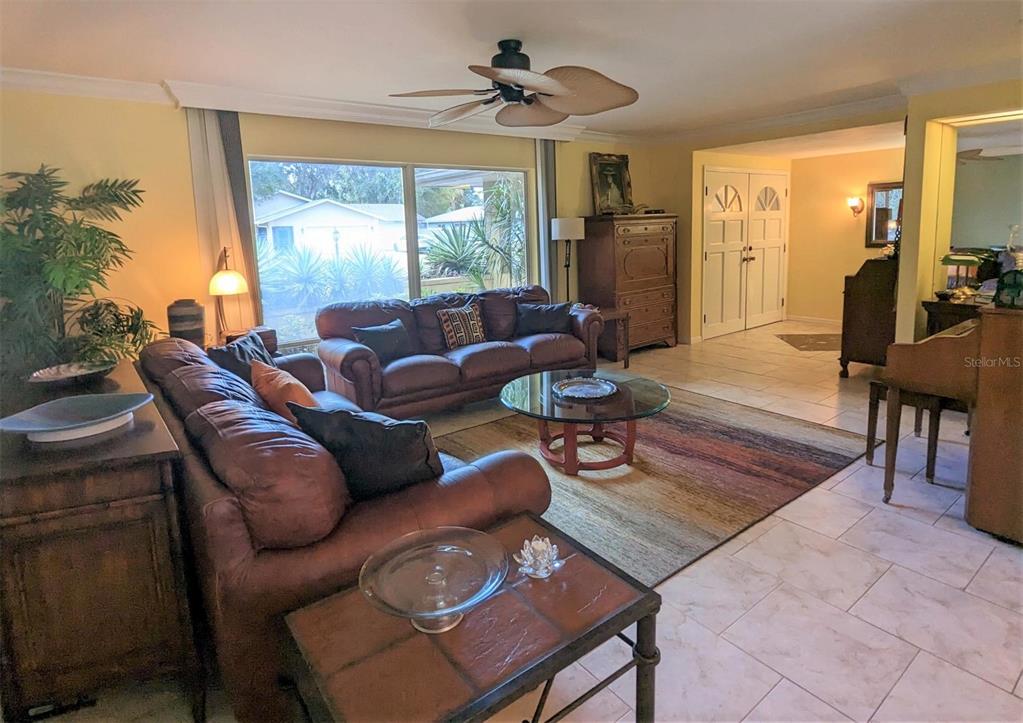 A living room features brown leather sofas, a glass coffee table, and tile flooring — 5409 PALM AIRE DRIVE, SARASOTA, FL