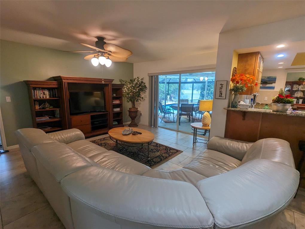 A living room features a large white sectional sofa, a wooden entertainment center, and sliding doors — 5409 PALM AIRE DRIVE, SARASOTA, FL