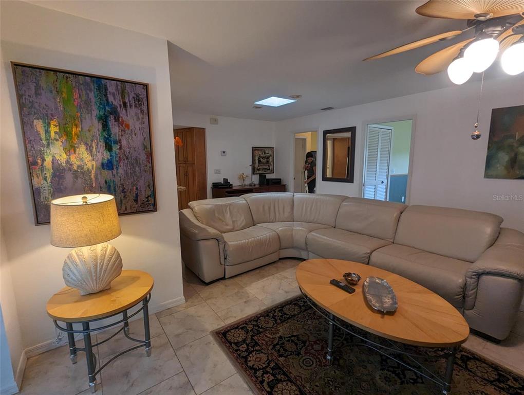 A living room features a large beige sectional sofa, a coffee table, and tile flooring — 5409 PALM AIRE DRIVE, SARASOTA, FL
