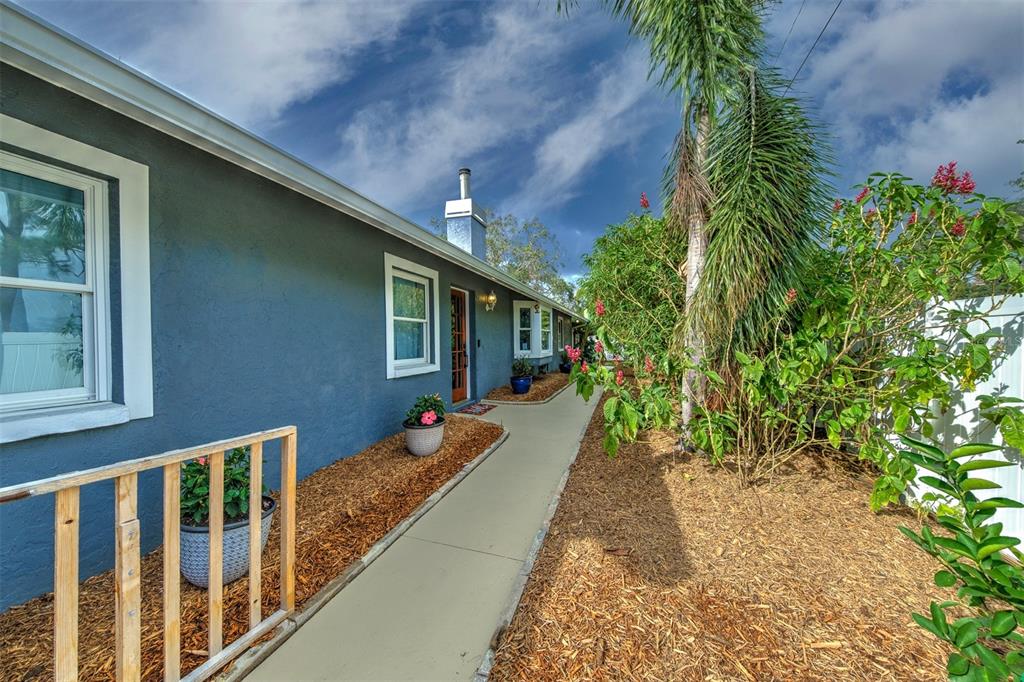A blue house exterior features a concrete walkway, wood mulch landscaping, and a palm tree — 2690 TEMPLE STREET, SARASOTA, FL