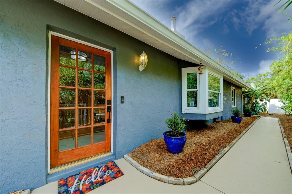 A blue house exterior features a wooden front door, a bay window, and a walkway — 2690 TEMPLE STREET, SARASOTA, FL