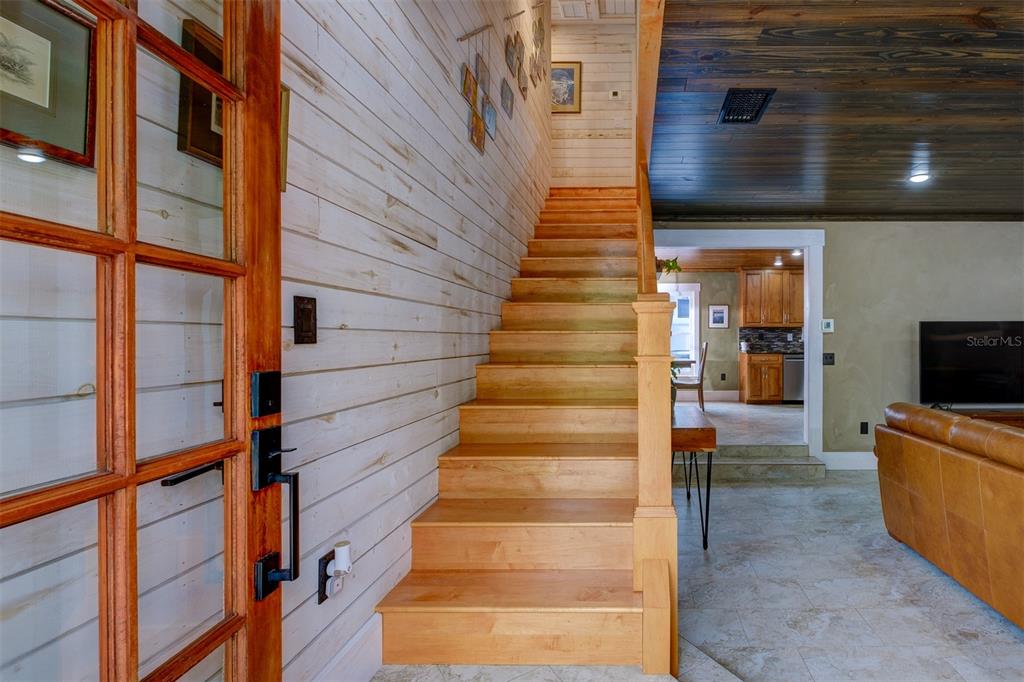 A wooden staircase with white shiplap walls leads upward next to a living area — 2690 TEMPLE STREET, SARASOTA, FL