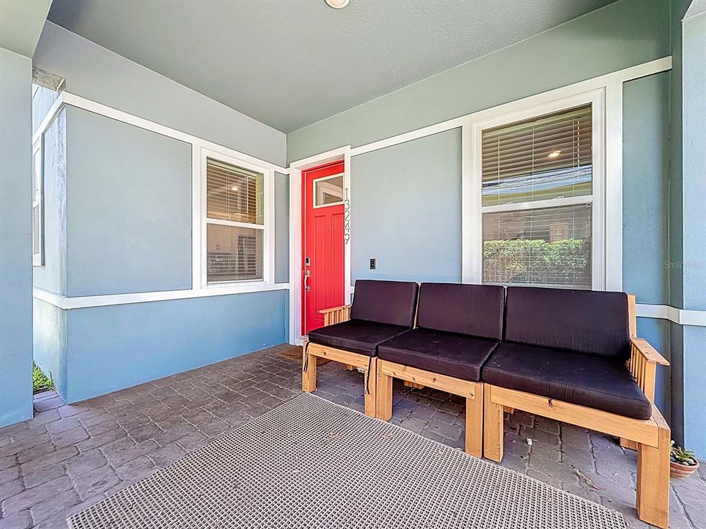 A covered front porch features light blue walls, a red door, and a wooden bench — 13249 CORMACK LANE, ORLANDO, FL