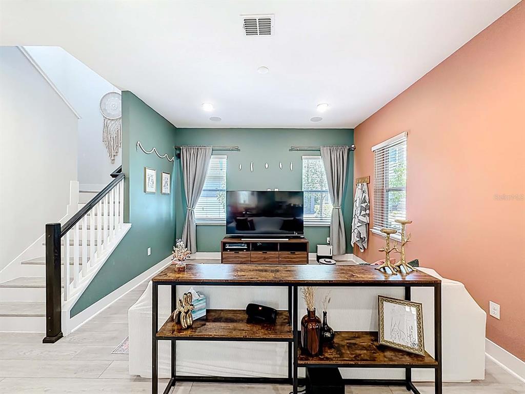 A living room features a green accent wall, a staircase, and a wooden console table — 13249 CORMACK LANE, ORLANDO, FL