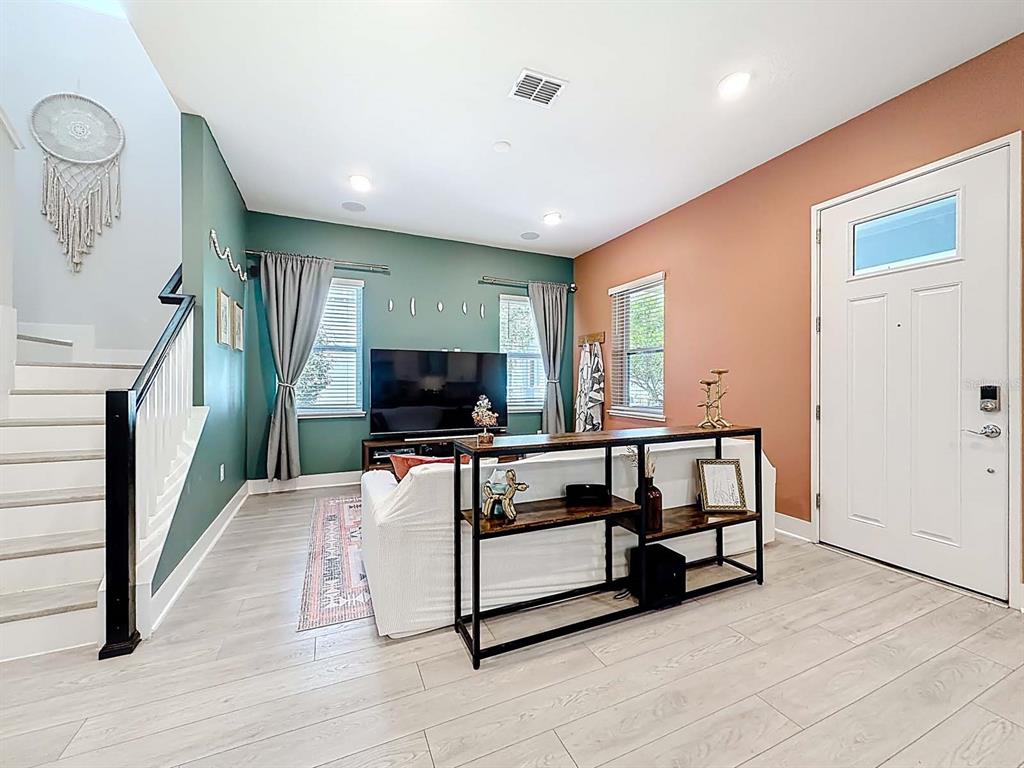 A living room features a green accent wall, a white sofa, and a console table — 13249 CORMACK LANE, ORLANDO, FL