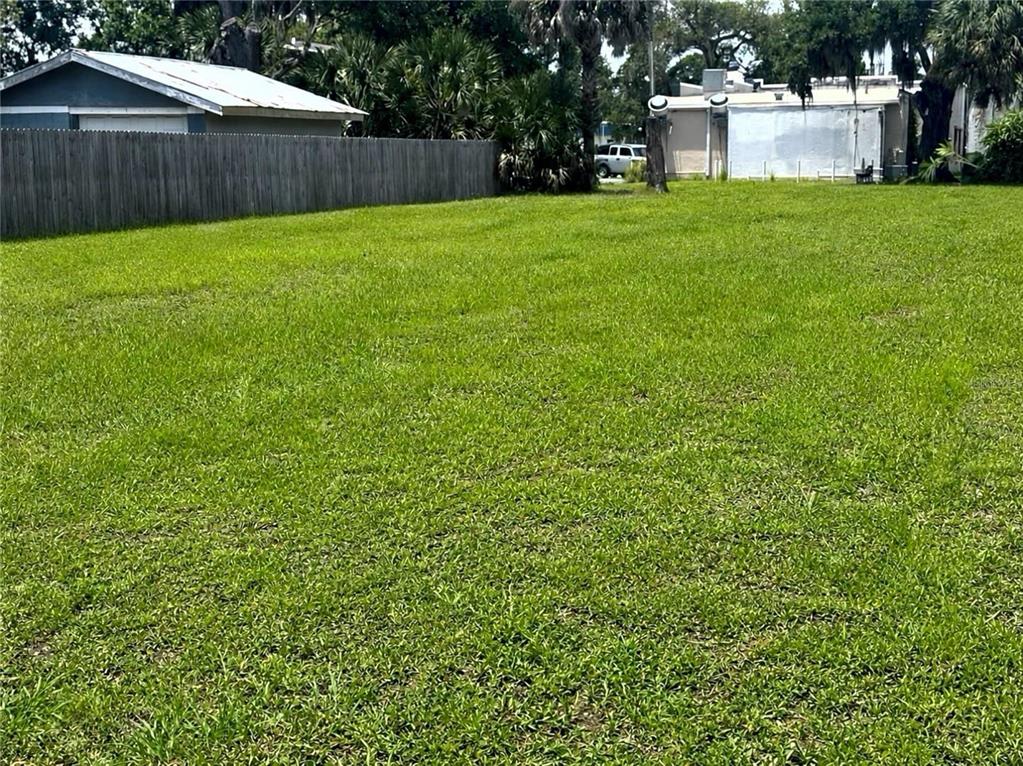 A large, flat, grassy residential lot enclosed by a wooden fence — 609 DOWNING STREET, NEW SMYRNA BEACH, FL