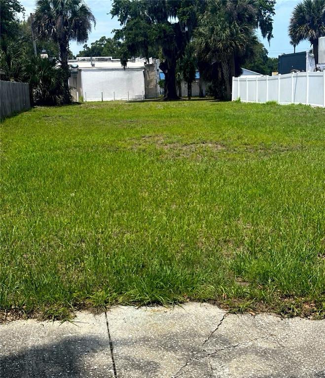 A vacant, grassy residential lot is bordered by a white fence and mature palm trees — 609 DOWNING STREET, NEW SMYRNA BEACH, FL