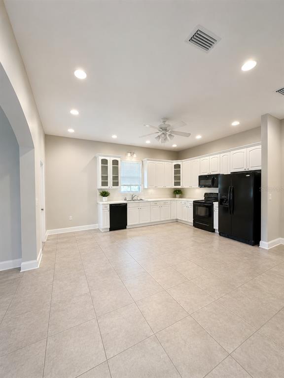 A kitchen with white cabinets, black appliances, and light tile flooring — 217 E 19TH AVENUE, MOUNT DORA, FL