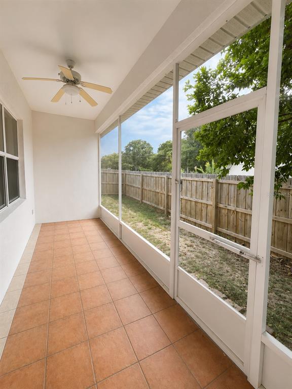 A screened-in patio features tan tile flooring, a ceiling fan, and a view of the yard — 217 E 19TH AVENUE, MOUNT DORA, FL