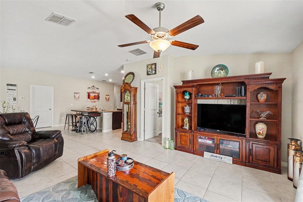 A living room features tile flooring, a large wooden entertainment center, and a ceiling fan — 14907 IMPERIAL PURPLE LANE, WIMAUMA, FL