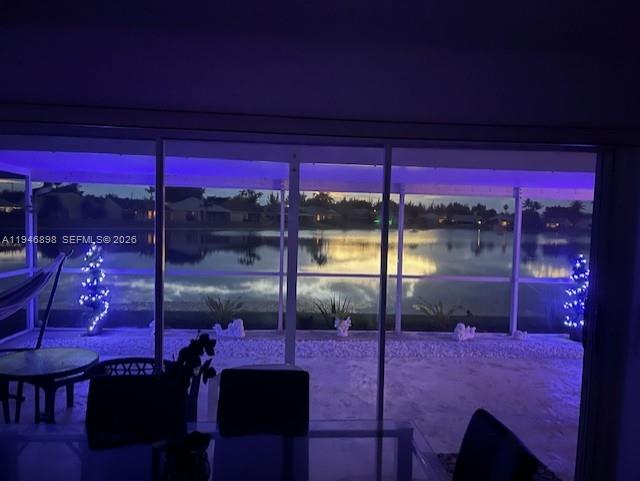 A view through a glass door shows a patio with blue lights overlooking a lake — 600 SE 25th Ln, Homestead FL 33033, HOMESTEAD, FL