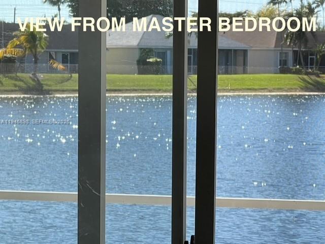 A view of a lake and neighboring houses seen through a sliding glass door — 600 SE 25th Ln, Homestead FL 33033, HOMESTEAD, FL