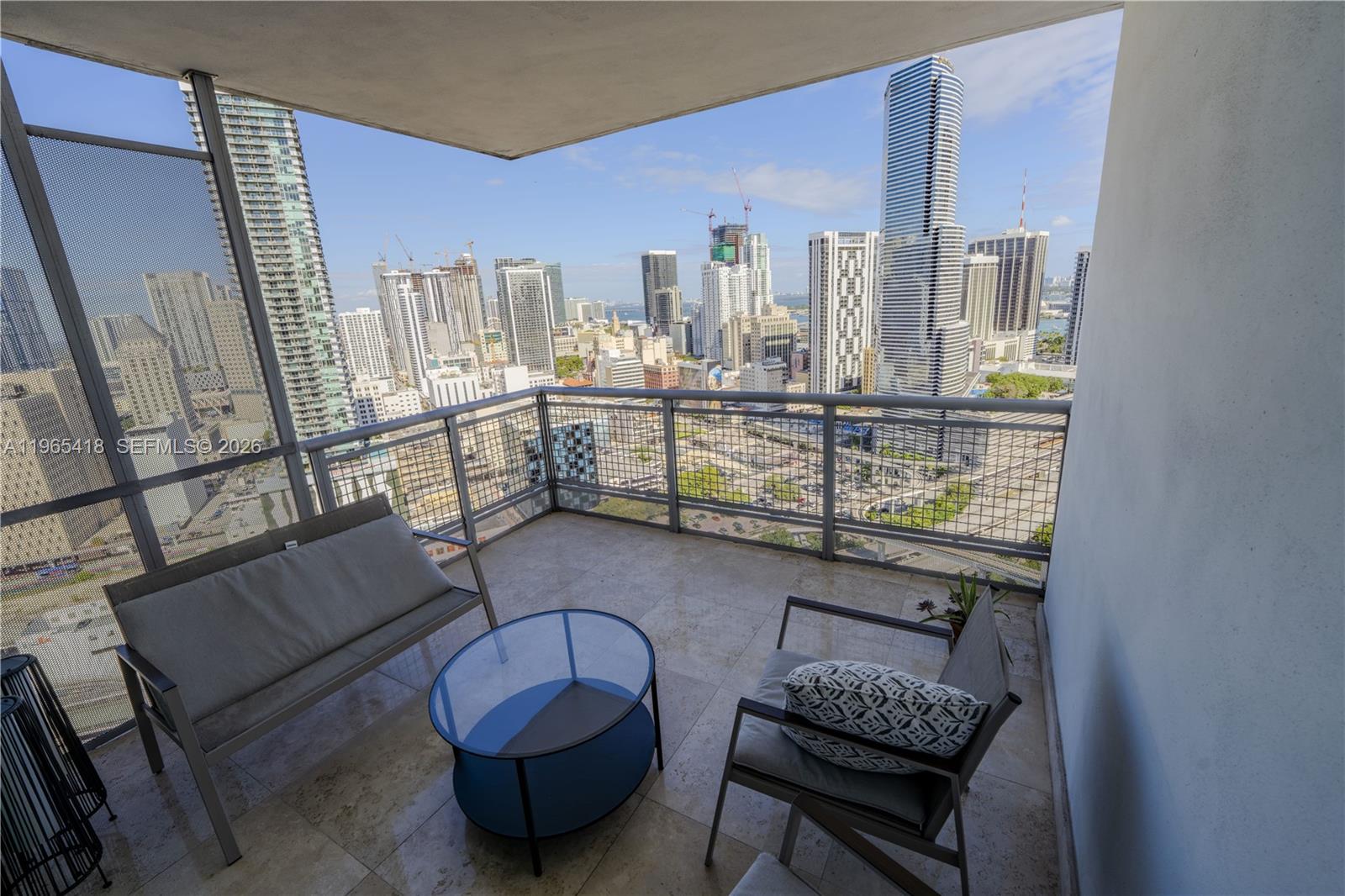A balcony with outdoor furniture overlooks a dense city skyline with multiple high-rise buildings — 350 S MIAMI AVE # 3203, Miami FL 33130, MIAMI, FL