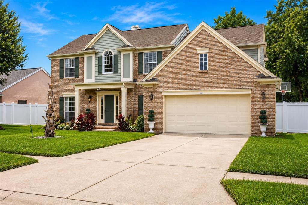 A two-story brick house with a front-facing garage, green shutters, and a concrete driveway — 1339 OLYMPIA PARK CIRCLE, OCOEE, FL