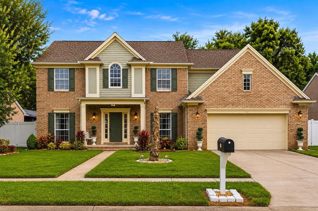 A two-story brick and siding house with a front porch, garage, and manicured lawn — 1339 OLYMPIA PARK CIRCLE, OCOEE, FL