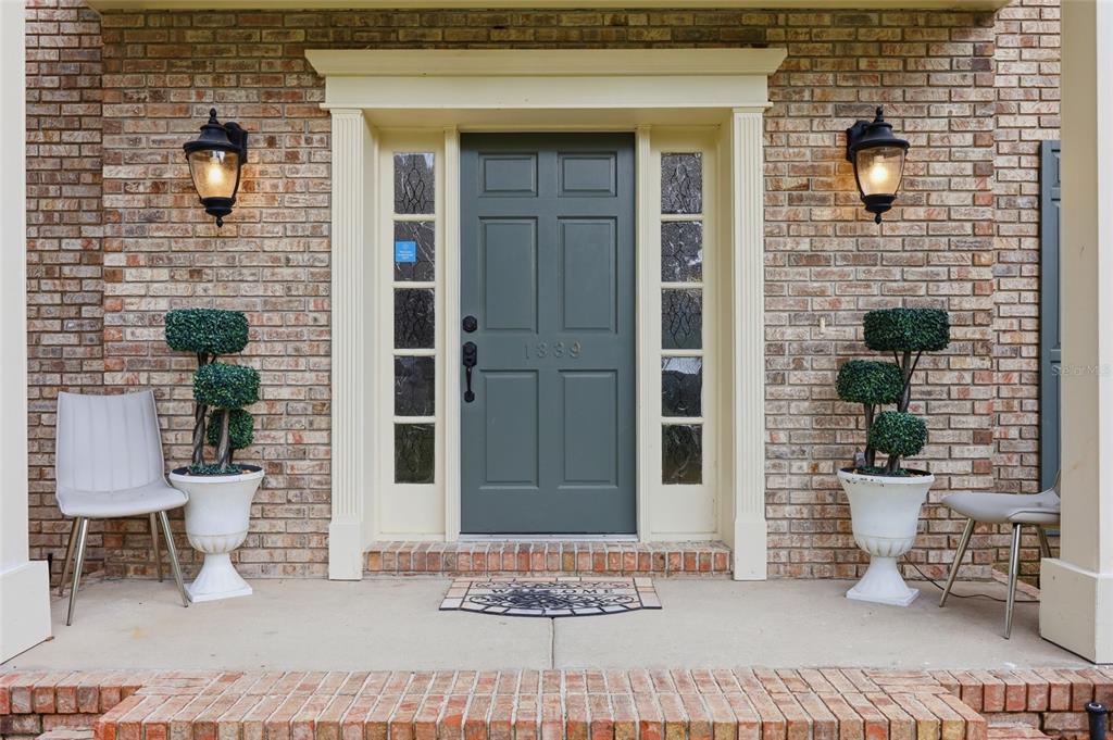 A front entryway features a green door with sidelights, brick walls, and two potted topiaries — 1339 OLYMPIA PARK CIRCLE, OCOEE, FL