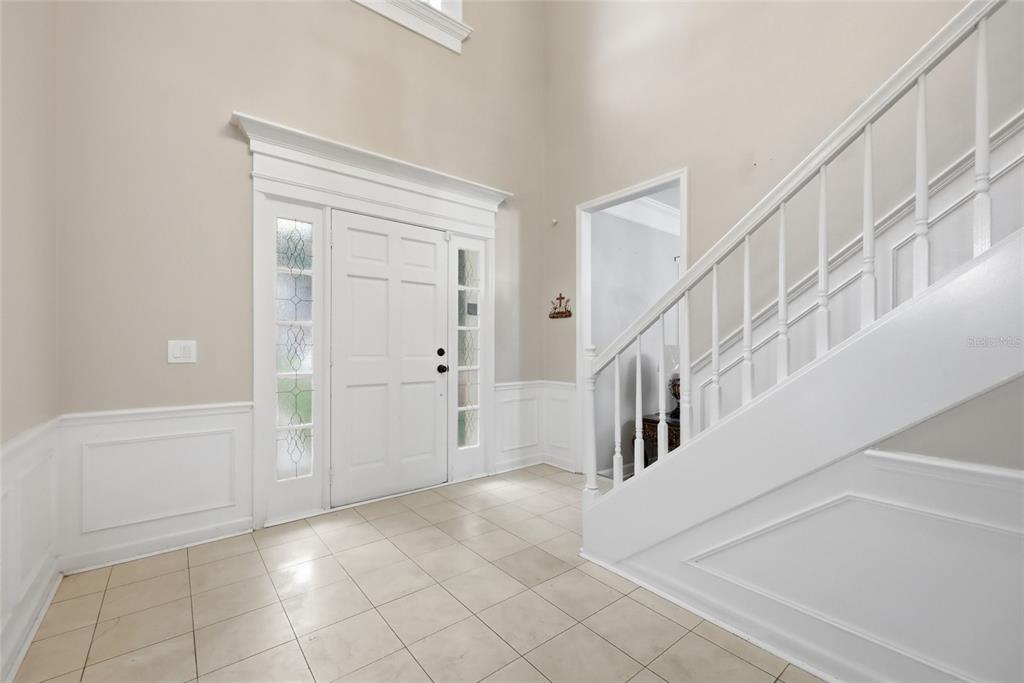 A bright foyer features a white front door, tiled floors, and a staircase with white railings — 1339 OLYMPIA PARK CIRCLE, OCOEE, FL