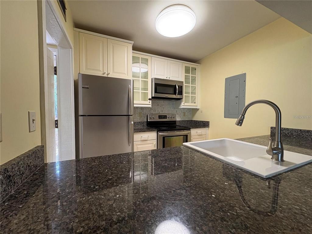A kitchen features dark granite countertops, white cabinetry, stainless steel appliances, and a white sink — 193 PALM VIEW COURT UNIT 3453/4, HAINES CITY, FL