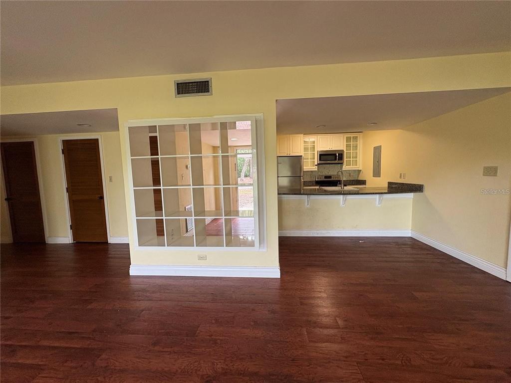 A room with wood-look flooring, a built-in white shelving unit, and an open kitchen — 193 PALM VIEW COURT UNIT 3453/4, HAINES CITY, FL