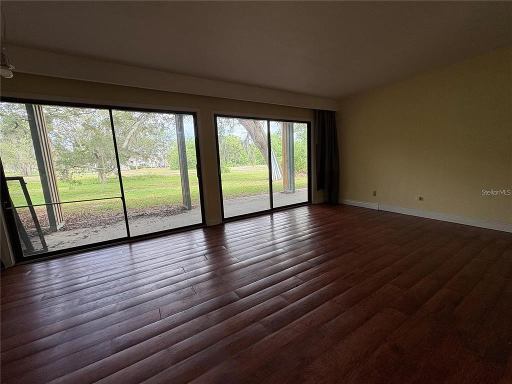 A room with dark wood-look flooring and two large sliding glass doors leading outside — 193 PALM VIEW COURT UNIT 3453/4, HAINES CITY, FL