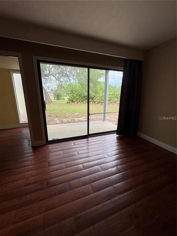 A room with dark wood flooring and a large sliding glass door leading to a patio — 193 PALM VIEW COURT UNIT 3453/4, HAINES CITY, FL