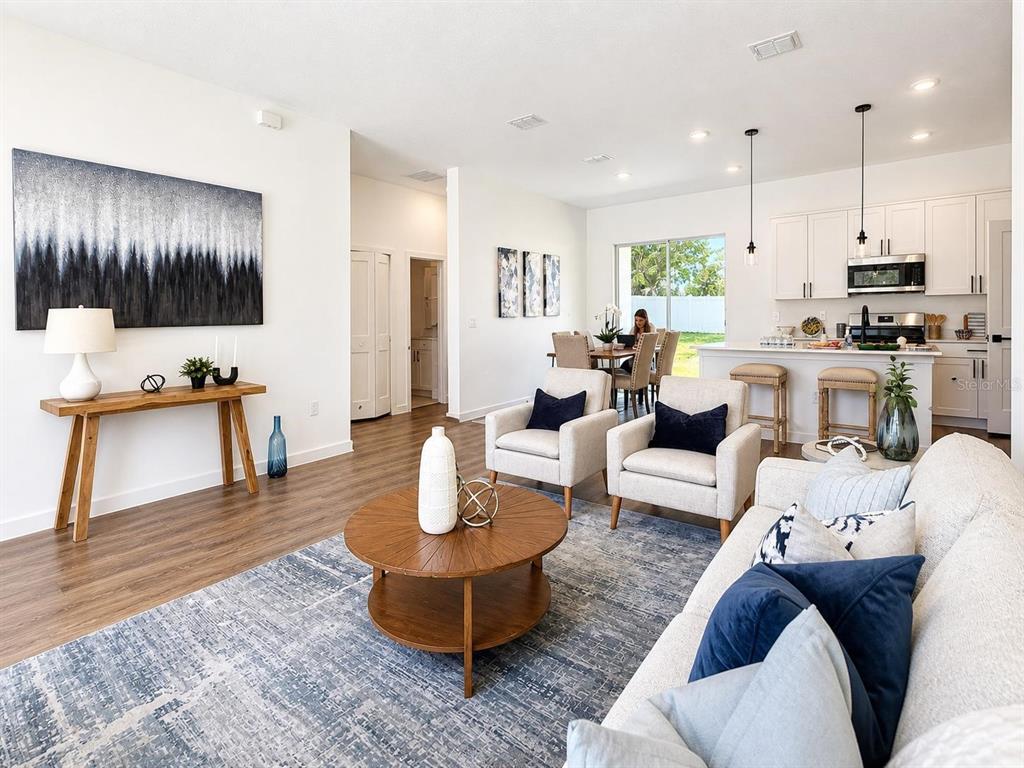 An open-concept living room and kitchen featuring wood flooring, a blue rug, and neutral furniture — 9509 N OLD MILL WAY, CITRUS SPRINGS, FL