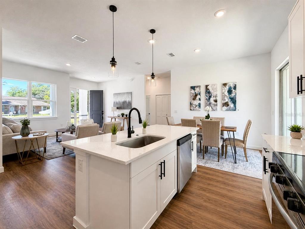 A kitchen island with a sink and pendant lights overlooks an open-concept living and dining area — 9509 N OLD MILL WAY, CITRUS SPRINGS, FL